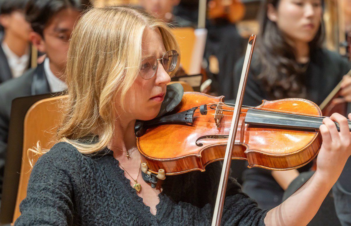 Hannah playing in rehearsal, among the orchestra