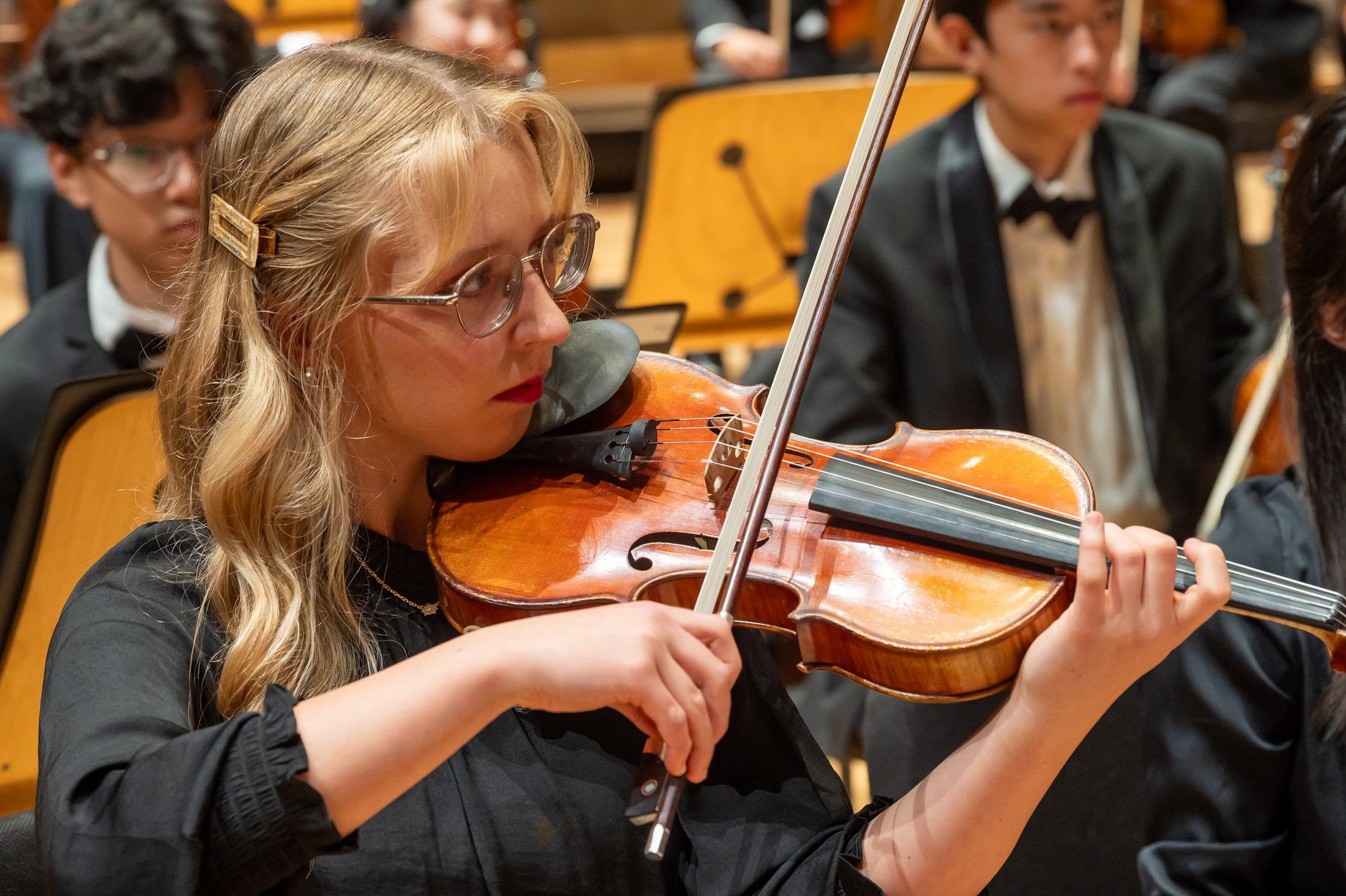 Hannah performing in orchestra, bow drawn across the string